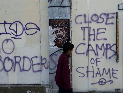 Un ni&ntilde;o pasa delante de unas pintadas hechas en Atenas a mediados de abril durante una manifestaci&oacute;n contra la guerra en Siria y la actitud de la UE hacia los refugiados. 