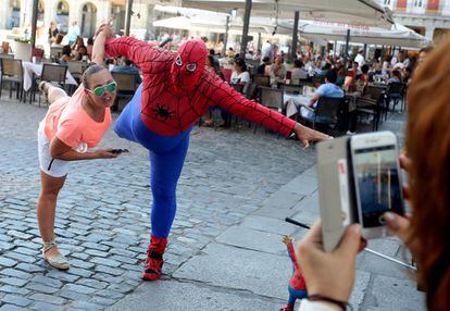El Spiderman Gordo de la plaza Mayor, durante una actuaci&oacute;n con una turista.