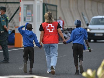 Una trabajadora de la Cruz Roja escolta a dos menores llegados al puerto de La Estaca (isla de El Hierro) en una imagen de archivo.