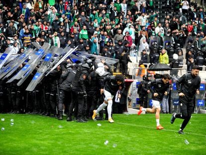 Jugadores y antidisturbios escapan durante los incidentes violentos dirigidos contra el equipo kurdo Admespor, mientras se lanzan objetos al campo en un partido de fútbol entre el equipo de fútbol turco Bursaspor y el Amedspor de Diryabakir, en Bursa el 5 de marzo de 2023.