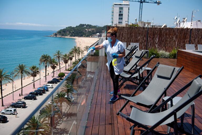 Una empleada limpia tumbonas en una terraza de un hotel en Lloret de Mar.