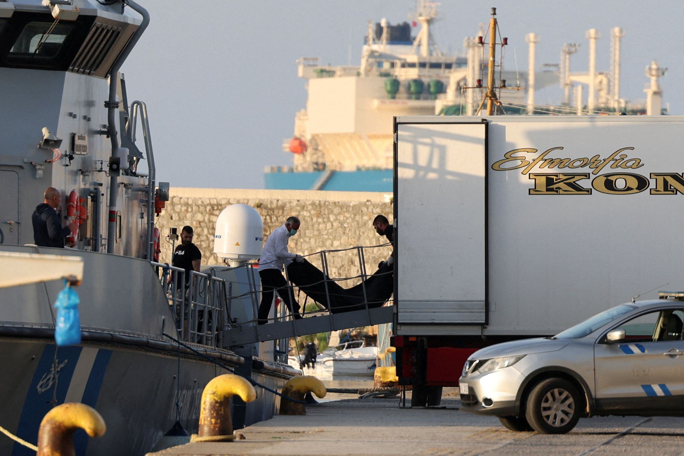 Traslado de una bolsa con el cadáver de uno de los migrantes muertos en el naufragio de un pesquero en el mar Jónico, este jueves, en el puerto de Kalamata.