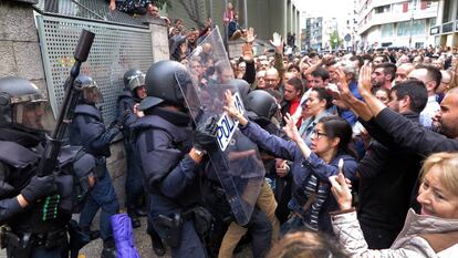 Votantes de un colegio electoral de Girona forcejean con agentes antidisturbios de la Policía Nacional que acudieron a clausurar el centro e incautarse de las urnas.