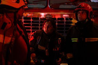 Tres bomberos fotografiados en los alrededores del edificio en llamas.