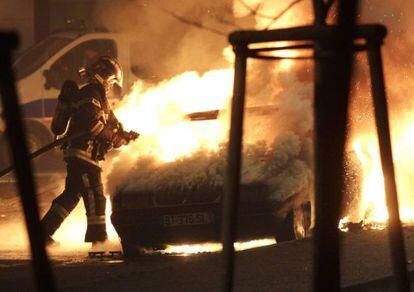 Un bombero intenta apagar el incendio en un coche en Nochevieja en Estrasburgo. 