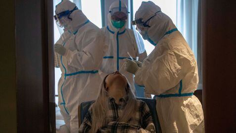 A woman takes a COVID-19 test at a quarantine hotel in Wuhan in central China's Hubei province on Tuesday, March 31, 2020. China on Tuesday reported just one new death from the coronavirus and a few dozen new cases, claiming that all new cases came from overseas. (AP Photo/Ng Han Guan)