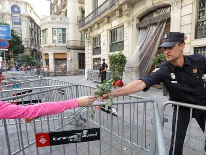 Una ciudadana entrega varias flores a un policía en Barcelona. En vídeo, imágenes de ciudadanos llevando flores a la policía.