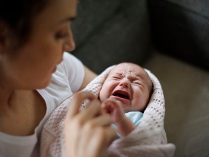 Un recién nacido llora en brazos de su madre.