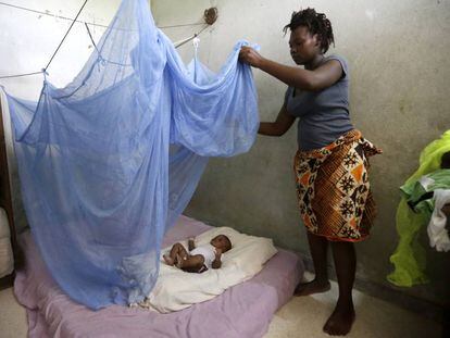 Una mujer cubre a su hijo con una mosquitera en Costa de Marfil para protegerle de la malaria.