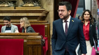 El 'president' Pere Aragonés (centro), acompañado por la consejera de Presidencia, Laura Vilagrá (der.) pasan al lado de la bancada de En Comú Podem en el Parlament.