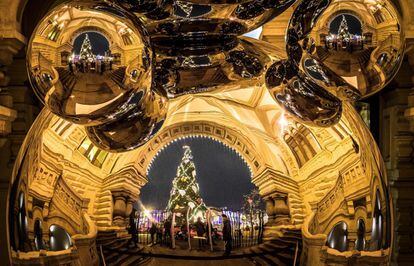 Un árbol de Navidad se refleja en una escultura de acero inoxidable situada en las afueras de los grandes almacenes GUM, en el centro de Moscú (Rusia), el 29 de noviembre de 2017.