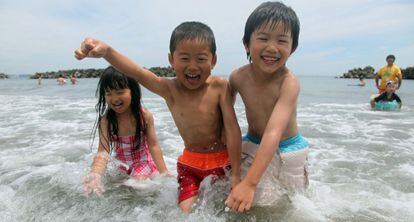 Tres niños se bañan en la playa de Nakoso.