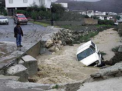 Un hombre observa el coche del hombre desaparecido en Riogordo, que fue arrastrado por un arroyo que pasa por el municipio.