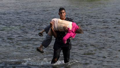 Un migrante venezolano carga una mujer para cruzar el Río Bravo en Coahuila, México. 