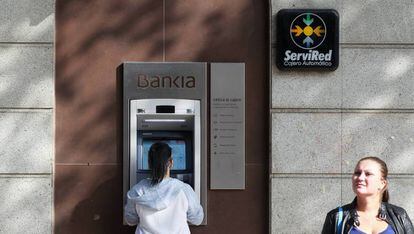 Una cliente opera en un cajero de Bankia.