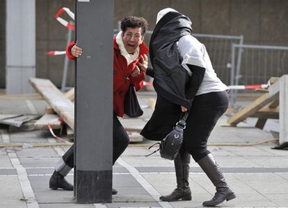 Dos mujeres se sujetan a un poste debido a la fuerza del viento, en Frankfurt Main, (Alemania).