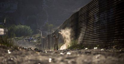 Un niño junto a la valla fronteriza que se alarga por Tijuana hasta adentrase en el mar.