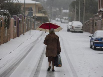 Una mujer camina por una calle nevada en Manzanares el Real esta mañana.