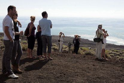 Varios turistas y curiosos observan desde una loma de Puerto Naos, cerca de La Restinga (El Hierro), el volcán submarino.