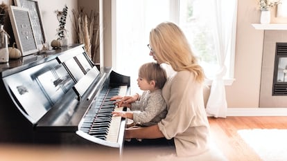 Una madre toca con su hijo el piano.
