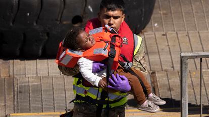 Un agente del personal militar trae a tierra a una niña que ha sido recogida por la fuerza fronteriza, en Dover (Inglaterra), este jueves.