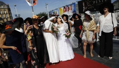 Un grupo de trabajadoras de un centro comercial vestidas de época, que celebran la jubilación de dos de ellas (vestidas de novias), pasan por la alfombra roja de la 65 edición del Festival Internacional de Cine San Sebastián.