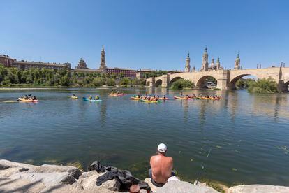 Varias personas en el río Ebro a su paso por Zaragoza, este sábado.