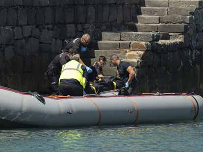 Dos trabajadores de traslados fúnebres y tres agentes de la Policía Nacional desembarcan el cadáver de la mujer embarazada que llegó sin vida al puerto de Arrecife (Lanzarote).
