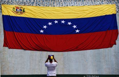 Un hombre saca una fotografía de la bandera nacional, en Caracas. 