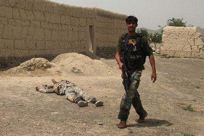 Un miembro de las fuerzas de seguridad afganas delante del cadáver de uno de los insurgentes muertos después de atacar una de las bases de la OTAN en Afganistán