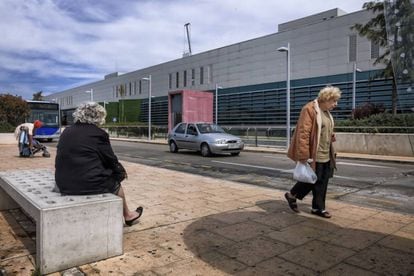 Usuarios del transporte público esperan la llegada del autobús en el hospital universitario Son Espases, en Palma.