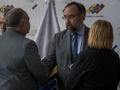 El presidente del Consejo Nacional Electoral (CNE) de Venezuela, Elvis Amoroso (i), estrecha la mano del presidente de la Comisión Nacional de Primarias, Jesús María Casal (c), tras ofrecer una rueda de prensa, en Caracas.