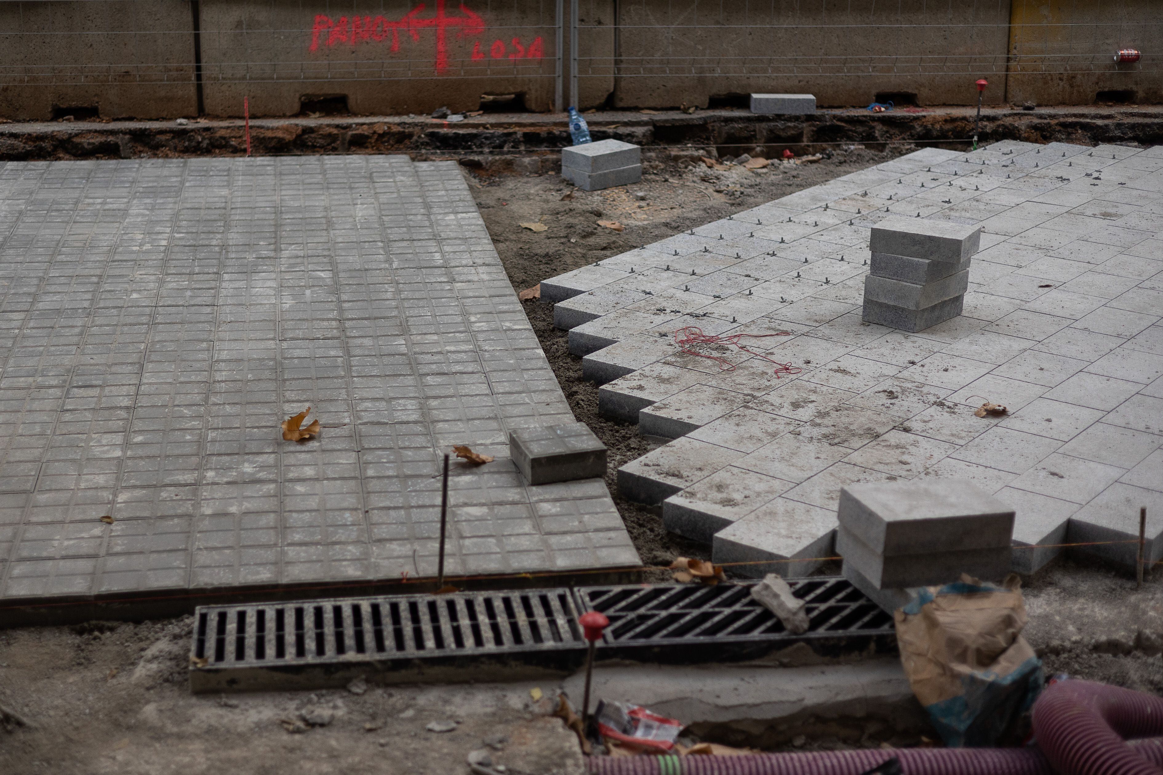 El pavimento que estrenarán los 'ejes verdes' de la Superilla de Barcelona incluye piezas rectangulares de granito colocadas al bies que requieren pericia al colocarlas, explican los obreros.