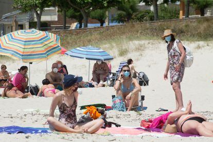 Varias personas protegidas con mascarillas toman el sol en la playa de A Rapadoira, en Foz, en la comarca de A Mariña, Lugo, este jueves.