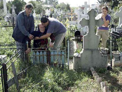 La familia de Marian Milita, en Targoviste. Arriba, sus hermanas sostienen a la madre, Elvira, en el cementerio del pueblo donde quieren enterrarlo, bajo la mirada de Izabela, la hija de Marian. Abajo, en la casa familiar.