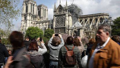 Varios transeúntes sacan fotos de Notre Dame, el miércoles 17 de abril.