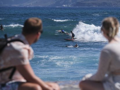 Dos turistas observan a los surfistas en el municipio tinerfeño de Puerto de la Cruz, el pasado 27 de septiembre.