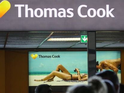 Pasajeros delante de un cartel publicitario de Thomas Cook en el aeropuerto de Francfort.