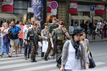 Una patrulla militar cruza una calle de París junto a varios ciudadanos.