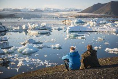 Dos viajeros contemplado los icebergs de la laguna de Jökulsárlón, en Islandia.