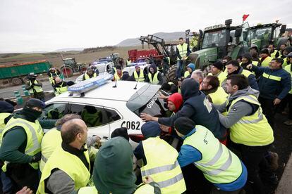 Un grupo de agricultores mueven  un coche de la Guardia Civil para acceder a Pamplona, el 8 de febrero.