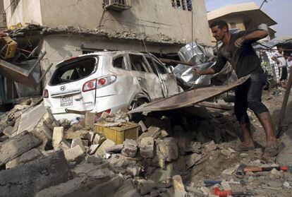 Un hombre quita escombros tras la explosi&oacute;n de un coche bomba en el barrio de Karada, en Bagdad, el pasado martes.