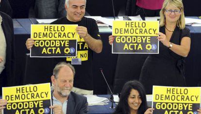 Eurodiputados de Los Verdes muestran carteles con el mensaje &quot;Hola democracia. Adi&oacute;s Acta&quot;.