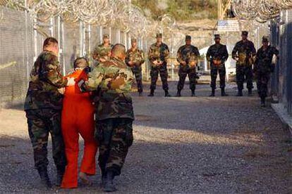 Dos soldados escoltan a un detenido en la base naval de Guantánamo, en una imagen tomada en enero de 2002.