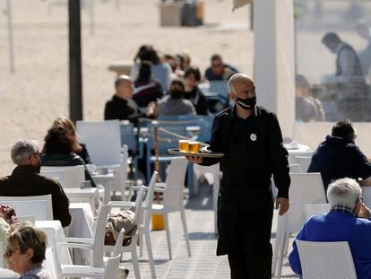 Un camarero atiende las mesas de una terraza de un bar en la playa de la Malvarrosa, en Valencia.