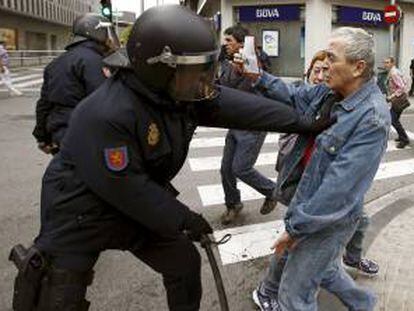 El diputado navarro de Amaiur Sabino Cuadra (d) muestra su documentación a un efectivo de la Policia Nacional durante los incidentes que se han registrado esta mañana en los alrededores de un centro comercial de Pamplona durante la huelga general.