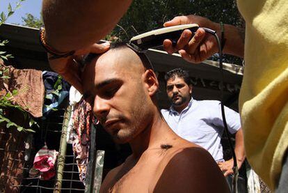 Un residente del poblado chabolista Puerta de Hierro le corta el pelo a un indignado.