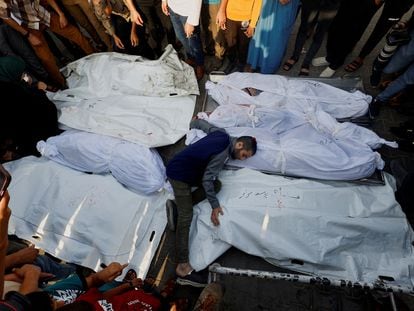 Un hombre coloca los cuerpos de las víctimas de un bombardeo israelí en Gaza durante un funeral en Jan Yunis, este martes.