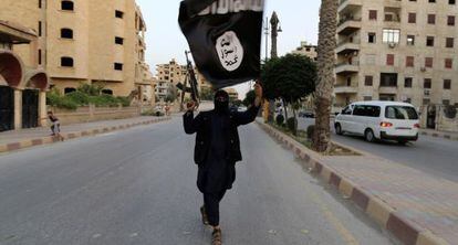 En junio de 2014, un miembro armado del Estado Isl&aacute;mico ondeaba una bandera en la ciudad siria de Raqqa, feudo de la organizaci&oacute;n yihadista.&ensp;