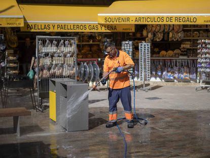 Un trabajador de la contrata municipal limpia unas papelera este martes en una calle del centro de Valencia.